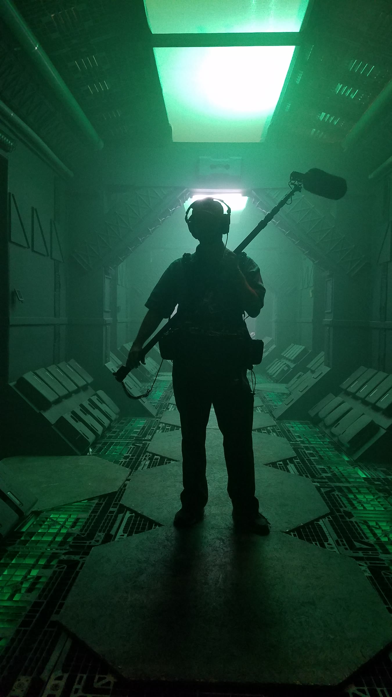 Barry Rathbun holding a boom pole, silhouetted in a green-lit corridor